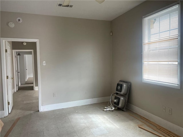 empty room featuring tile patterned floors, visible vents, baseboards, and plenty of natural light