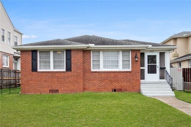 bungalow-style house featuring brick siding, roof with shingles, crawl space, fence, and a front lawn