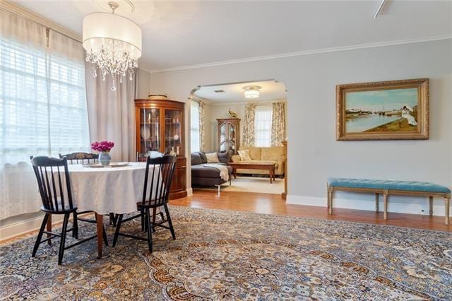 dining space with a notable chandelier, baseboards, wood finished floors, and crown molding