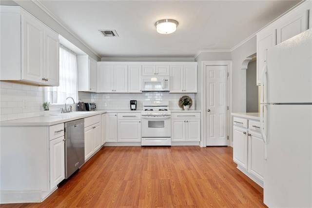 kitchen featuring white appliances, visible vents, light wood-style flooring, light countertops, and a sink