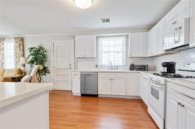 kitchen with white appliances, light countertops, a sink, and light wood finished floors