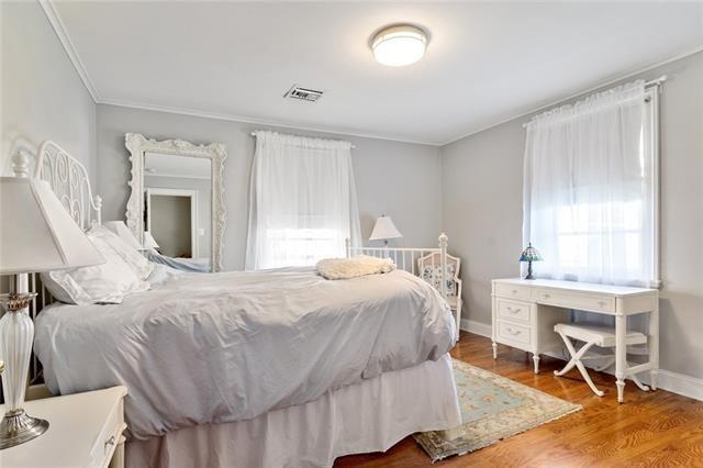 bedroom with baseboards, crown molding, visible vents, and wood finished floors