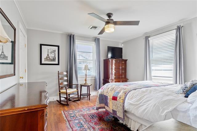 bedroom featuring baseboards, visible vents, crown molding, and wood finished floors