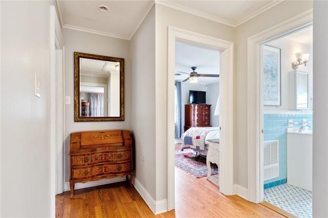 corridor with baseboards, ornamental molding, and light wood-style floors