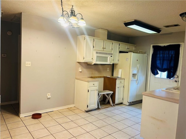 kitchen featuring light tile patterned floors, hanging light fixtures, white cabinets, a textured ceiling, and white appliances