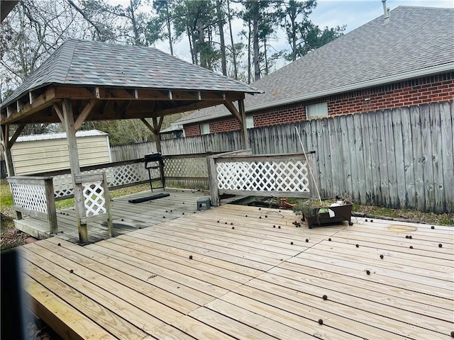 deck featuring a gazebo, a storage unit, an outdoor structure, and fence