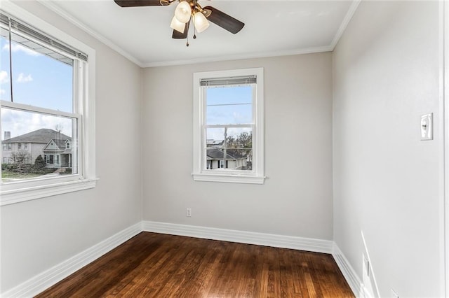 spare room featuring baseboards, crown molding, dark wood-style floors, and a healthy amount of sunlight