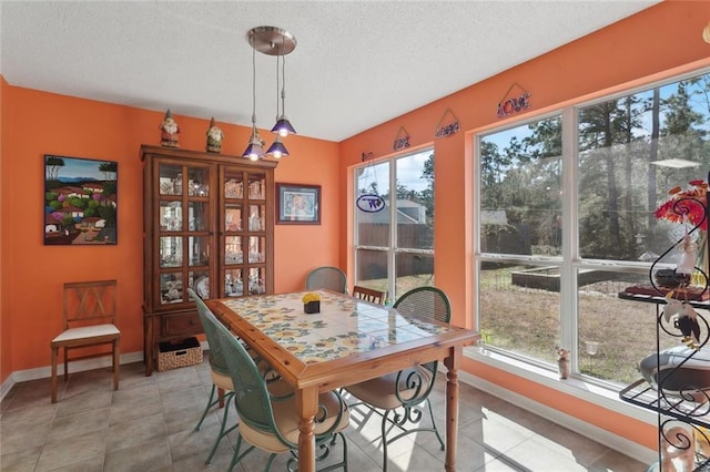 dining room with light tile patterned flooring, a textured ceiling, and baseboards