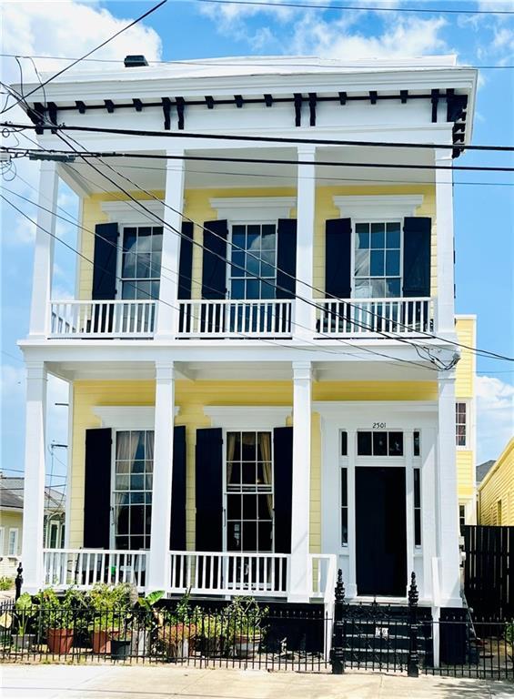 view of front of house with a balcony, a porch, and fence