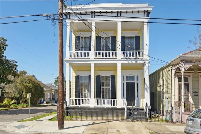 view of front of property featuring covered porch, a balcony, and fence