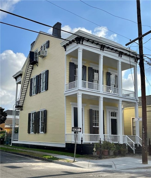 view of front of home with a balcony, a porch, and a chimney