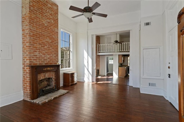 unfurnished living room featuring visible vents, a towering ceiling, a ceiling fan, and hardwood / wood-style floors