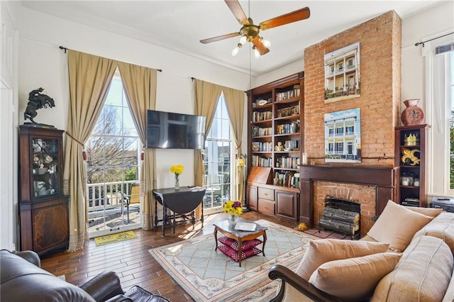 living area with a fireplace, a ceiling fan, and hardwood / wood-style flooring