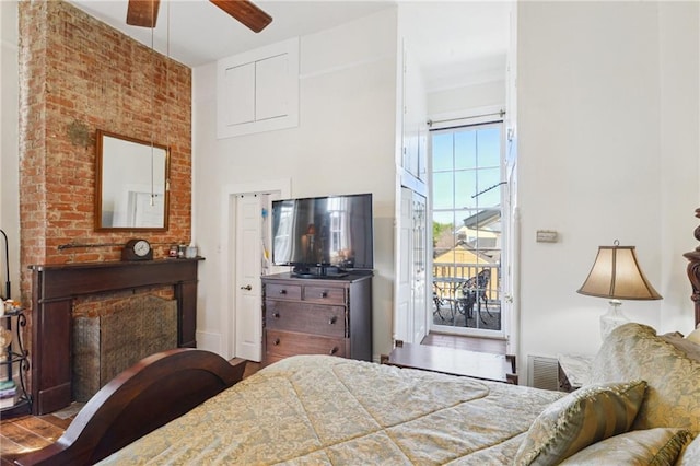 bedroom featuring access to exterior, visible vents, a towering ceiling, and wood finished floors