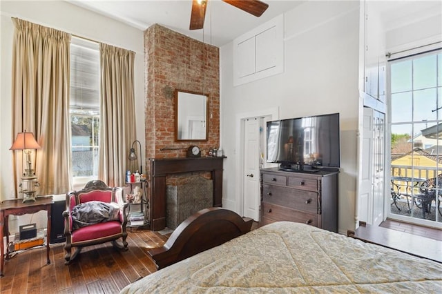 bedroom with multiple windows, wood-type flooring, a towering ceiling, and access to outside