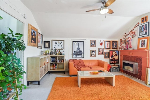 living area with a fireplace with flush hearth, ceiling fan, and lofted ceiling