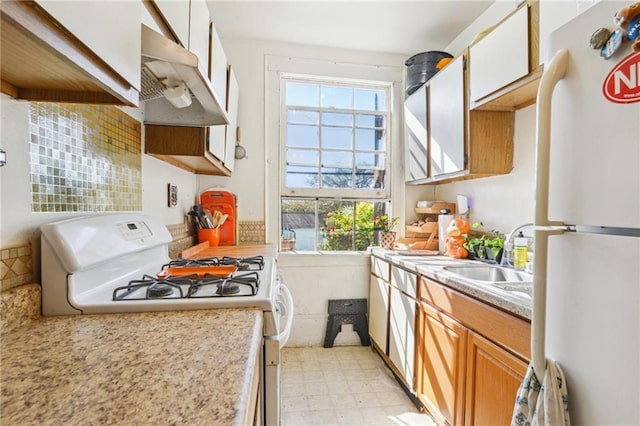 2501 Dauphine St, New Orleans, LA 70117 - kitchen with under cabinet range hood, light floors, light countertops, white appliances, and a sink