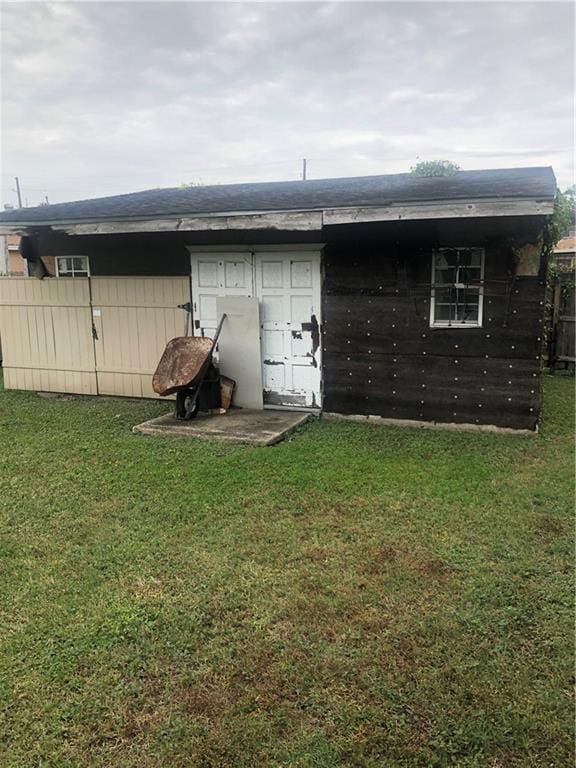 rear view of property featuring a yard and fence