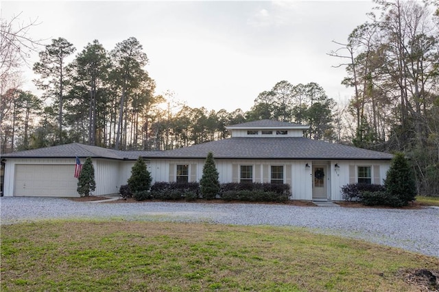 view of front of home with a garage, gravel driveway, and a front yard