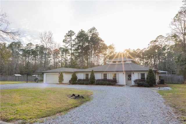 view of front of property featuring gravel driveway, a garage, fence, and a front lawn