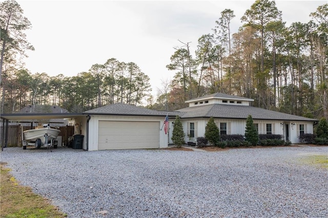 view of front facade with driveway, a carport, an attached garage, and fence