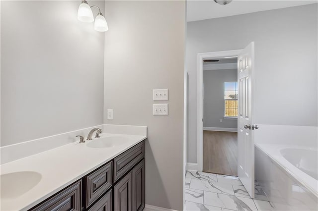 bathroom featuring marble finish floor, baseboards, a garden tub, and a sink