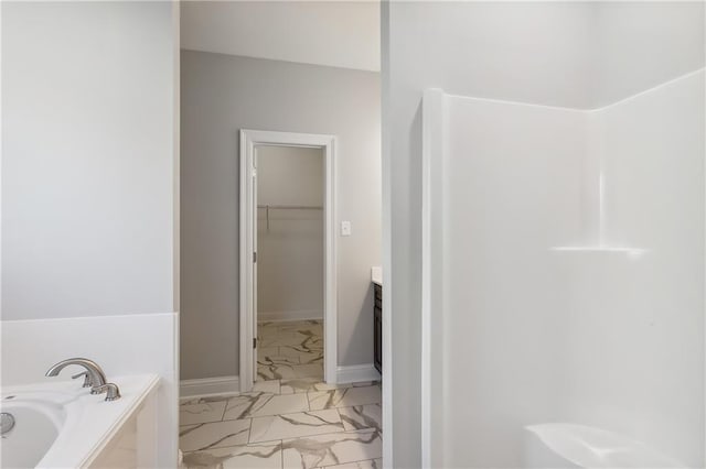 full bathroom featuring a walk in closet, marble finish floor, vanity, baseboards, and a bath