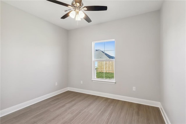 empty room with a ceiling fan, wood finished floors, visible vents, and baseboards