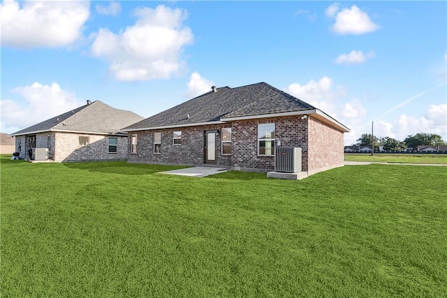 back of house featuring brick siding, roof with shingles, central AC unit, and a yard