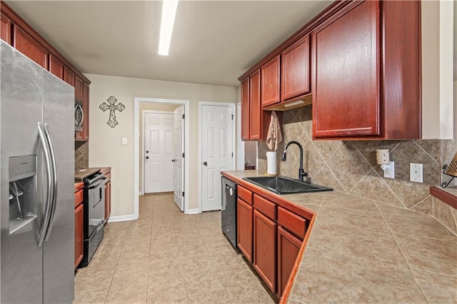 kitchen featuring black appliances, tile counters, decorative backsplash, and a sink