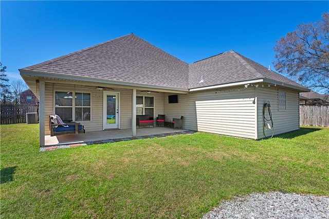 rear view of property featuring a lawn, ceiling fan, roof with shingles, fence, and a patio area