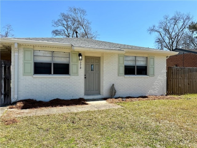 bungalow-style home featuring brick siding, a front yard, fence, and a shingled roof