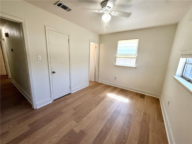 unfurnished bedroom featuring a ceiling fan, wood finished floors, visible vents, and baseboards