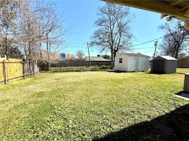 view of yard with a shed, a fenced backyard, and an outbuilding