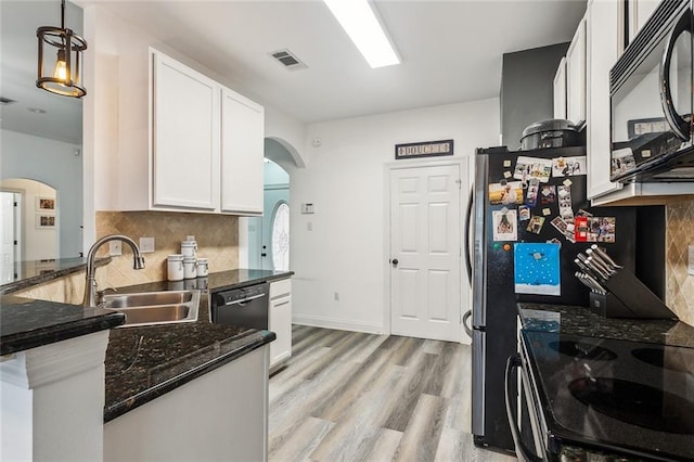 kitchen featuring a sink, visible vents, white cabinets, black appliances, and dark stone countertops