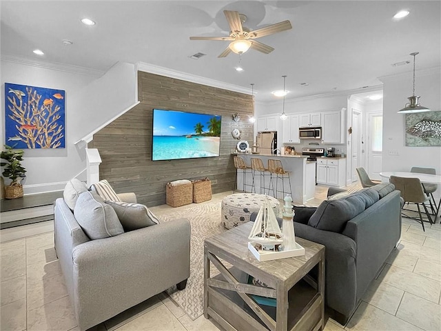 living room featuring recessed lighting, visible vents, an accent wall, ornamental molding, and a ceiling fan