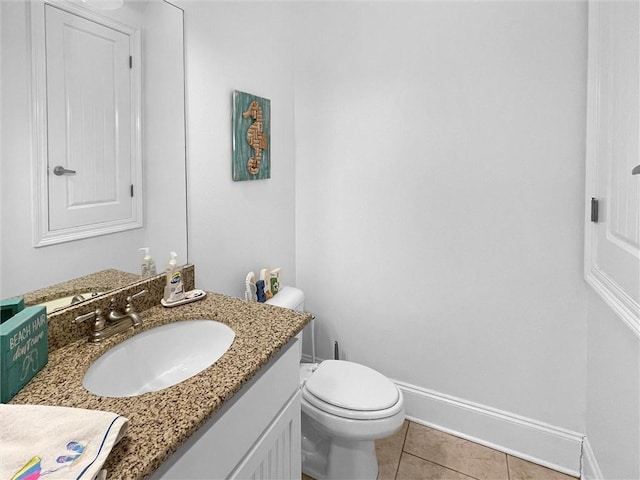 half bathroom with toilet, vanity, baseboards, and tile patterned floors