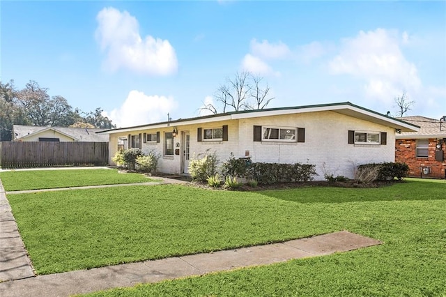 ranch-style house featuring brick siding, fence, and a front lawn