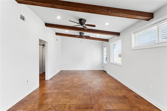 unfurnished room featuring a barn door, beamed ceiling, visible vents, and baseboards