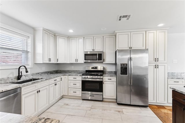 kitchen featuring visible vents, appliances with stainless steel finishes, light stone counters, a sink, and recessed lighting