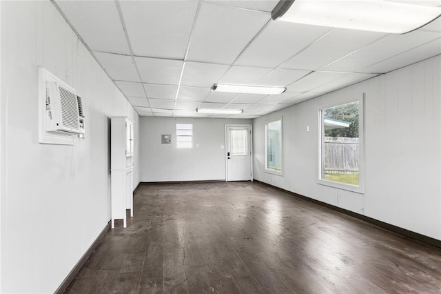 unfurnished room with baseboards, wood finished floors, a paneled ceiling, and a healthy amount of sunlight