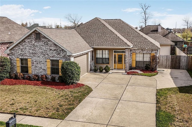 view of front of house with brick siding, an attached garage, fence, driveway, and a front lawn