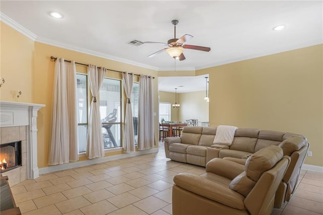 living area featuring light tile patterned floors, visible vents, ornamental molding, ceiling fan, and a tile fireplace