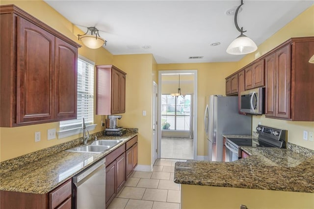 kitchen with visible vents, dark stone countertops, decorative light fixtures, stainless steel appliances, and a sink