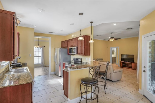 kitchen with visible vents, appliances with stainless steel finishes, open floor plan, a sink, and a kitchen breakfast bar