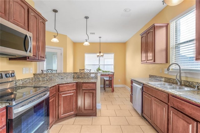 kitchen featuring pendant lighting, light tile patterned floors, appliances with stainless steel finishes, a sink, and a peninsula