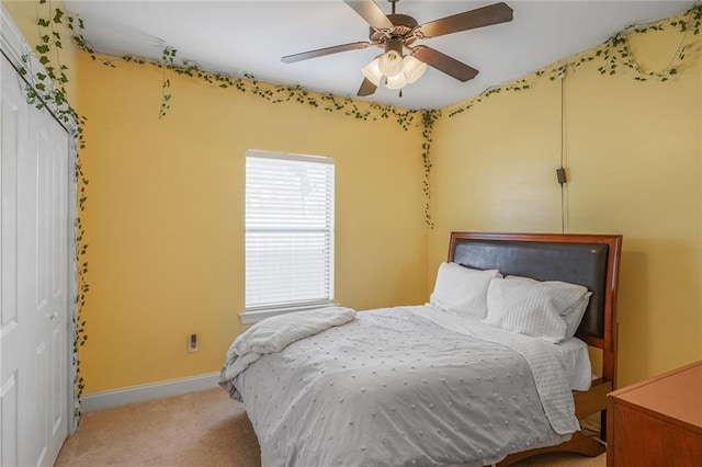 bedroom featuring light carpet, a closet, baseboards, and a ceiling fan