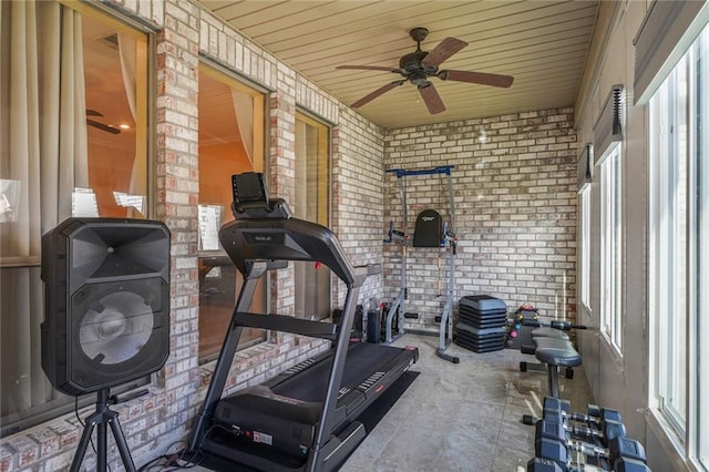 workout area featuring wooden ceiling, brick wall, and ceiling fan