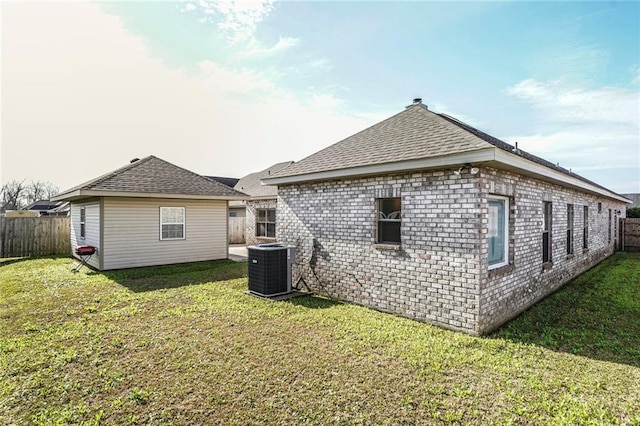 rear view of property with a yard, fence, and central air condition unit