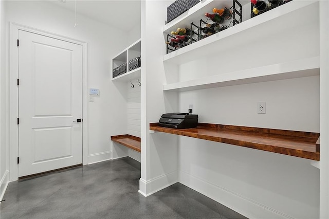 mudroom with built in desk, baseboards, and finished concrete floors